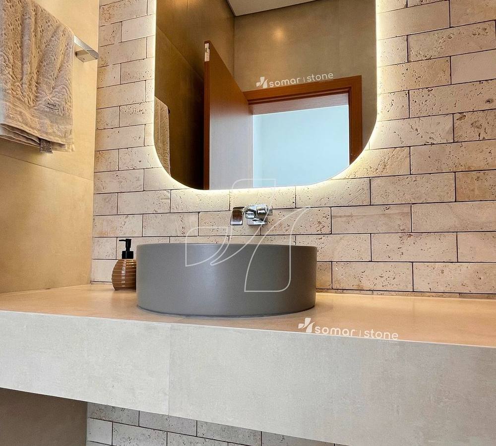 Lavabo com bancada em porcelanato e parede em travertino